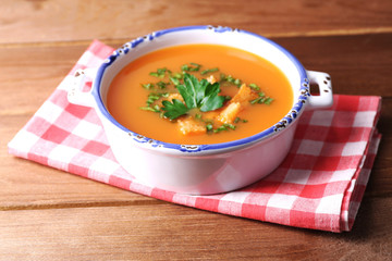 Carrot soup  in bowl, on wooden background