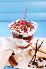 Tasty tiramisu dessert in glass, on color wooden background