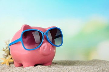 Fototapeta na wymiar Piggy bank with sunglasses on the beach