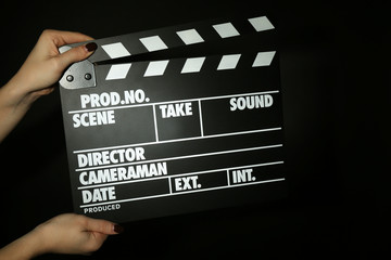 Movie clapper in female hand on dark color background