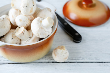 Whole champignons in a bowl on wooden boards