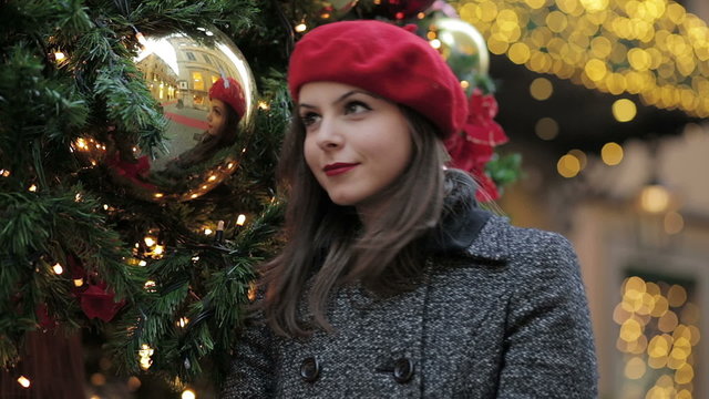 Happy woman using a christmas ball to reflect its image