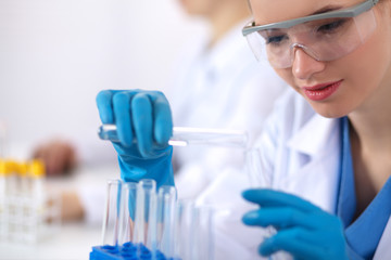 Fototapeta premium Woman researcher is surrounded by medical vials and flasks