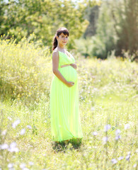 Lovely pregnant woman outdoors in sunny summer day