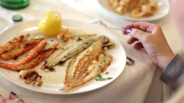 woman eats fish in seafood restaurant
