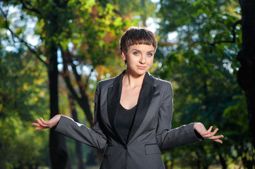 Helpless young business woman shrugs her shoulders