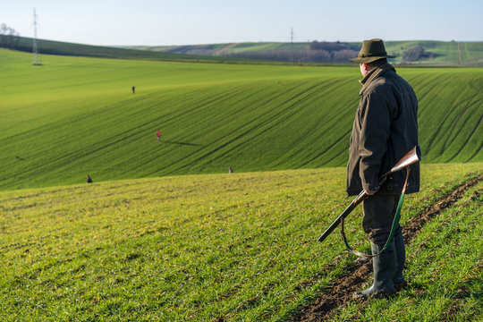 Gamekeeper walks over field.