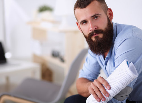 Young businessman sitting on chair with book in office
