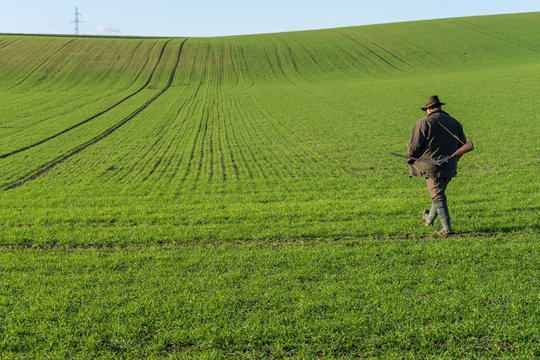 Gamekeeper walks over field.