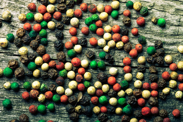 Colorful peppercorns on an old wooden table. Toned