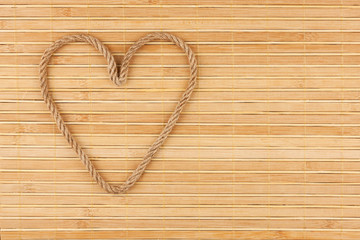 Symbolic heart made of rope lying on a bamboo mat