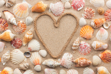 Symbolic heart made from rope and seashells lying on the sand