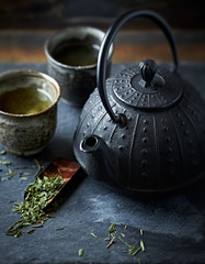 Obraz na płótnie Canvas A cast iron tea pot and green tea in ceramic cups