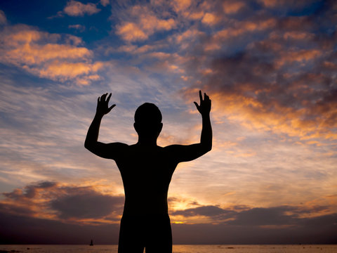 Silhouette of man surrendering with two hands raised in air near