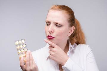 Junge Frau mit Tabletten in der Hand überlegt