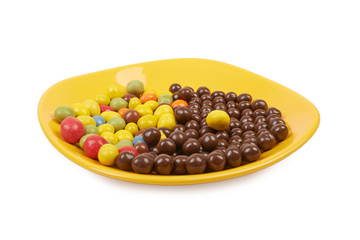 Chocolate balls and multicolored peanut glaze on a yellow plate