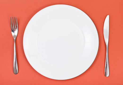 top view of porcelain plate, fork, knife on red