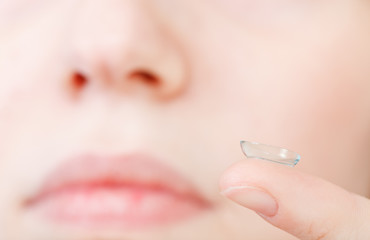 corrective lens on finger near female face