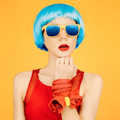 fashion lady in blue wig and sunglasses on bright yellow backgro