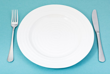 empty white plate with fork and knife on green