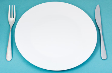 white porcelain plate with fork and knife on green