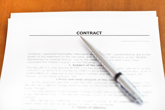 silver pen on sheet of sales contract on table