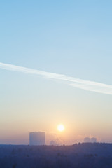 Fototapeta na wymiar sunrise sun in blue sky over city in cold winter