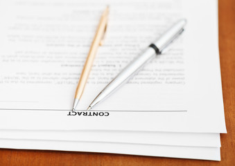 pages of sales contract and two pens on table