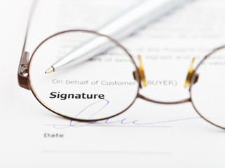 signature of agreement and pen through eyeglasses