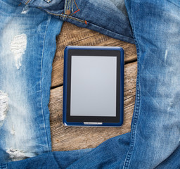 Jeans around mobile tablet pc on old wooben background