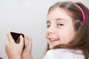 Fototapeta premium Cute little girl using modern smartphone
