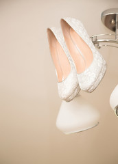 whithe high heel woman shoes hanging on chandelier
