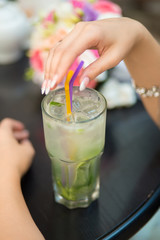 Woman hands with Mojito cocktail in a restaurant on a rustic woo
