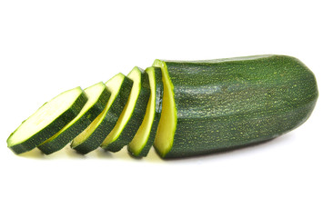 Half zucchini with some slices on white background.