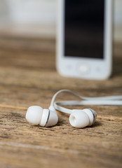 White smart phone with earphones and isolated screen on old wood