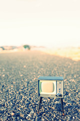 何もない道路の上に置かれた古いテレビ