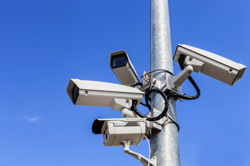 four cctv on metal light pole, blue sky background