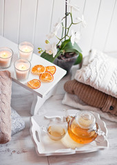 Tea-tray with hot grass drink, knitting clothes, dry oranges, ca