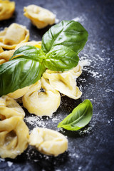 Homemade raw Italian tortellini and basil leaves