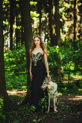 portrait of a girl in a dark dress with a dog in the forest