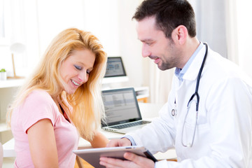 Fototapeta premium Young doctor showing results on tablet to patient
