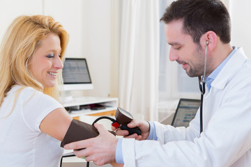 Young attractive doctor checking patient's blood pressure