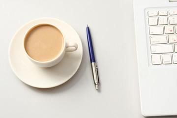 A cup of coffee and a pen near a laptop. Business concept.