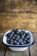 Blueberries in rustic kitchen setting with old wooden background