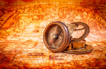 Vintage compass lies on an ancient world map.