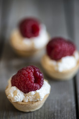 Raspberry tartlets on rustic wooden kitchen  background