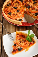Tomato tart with olives on wooden background