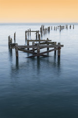Peaceful concept landscape image of smooth sea and pier ruins