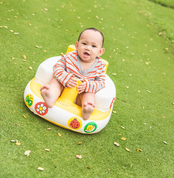 baby luagh when sit on the seat at the green grass field park