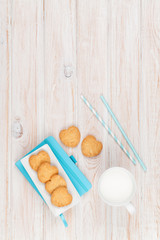 Cup of milk, heart shaped cookies and notepad
